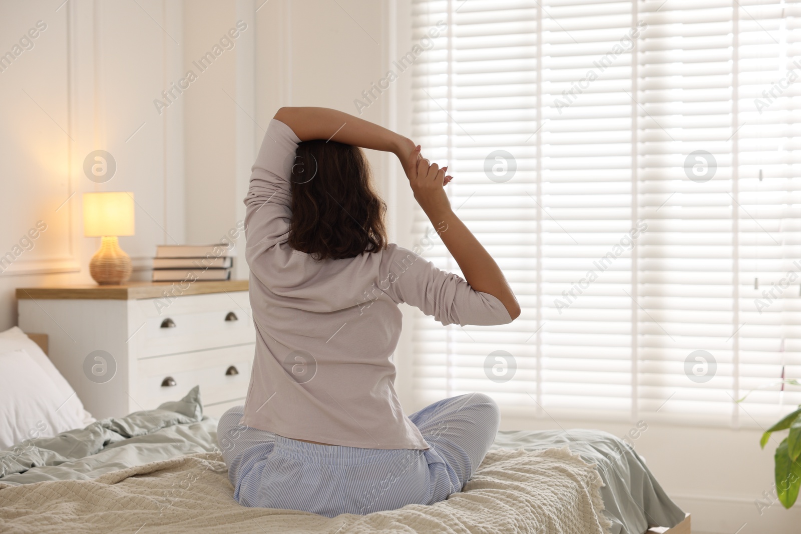 Teenage girl stretching on bed at home, back view Photo of Teenage girl stretching on bed at home, back view