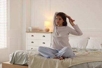 Photo of Teenage girl stretching on bed at home, space for text