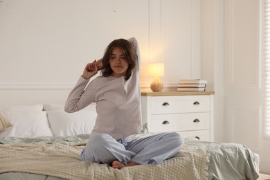 Photo of Teenage girl stretching on bed at home