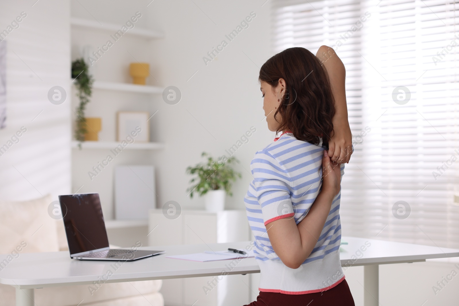 Photo of Teenage girl stretching at table at home