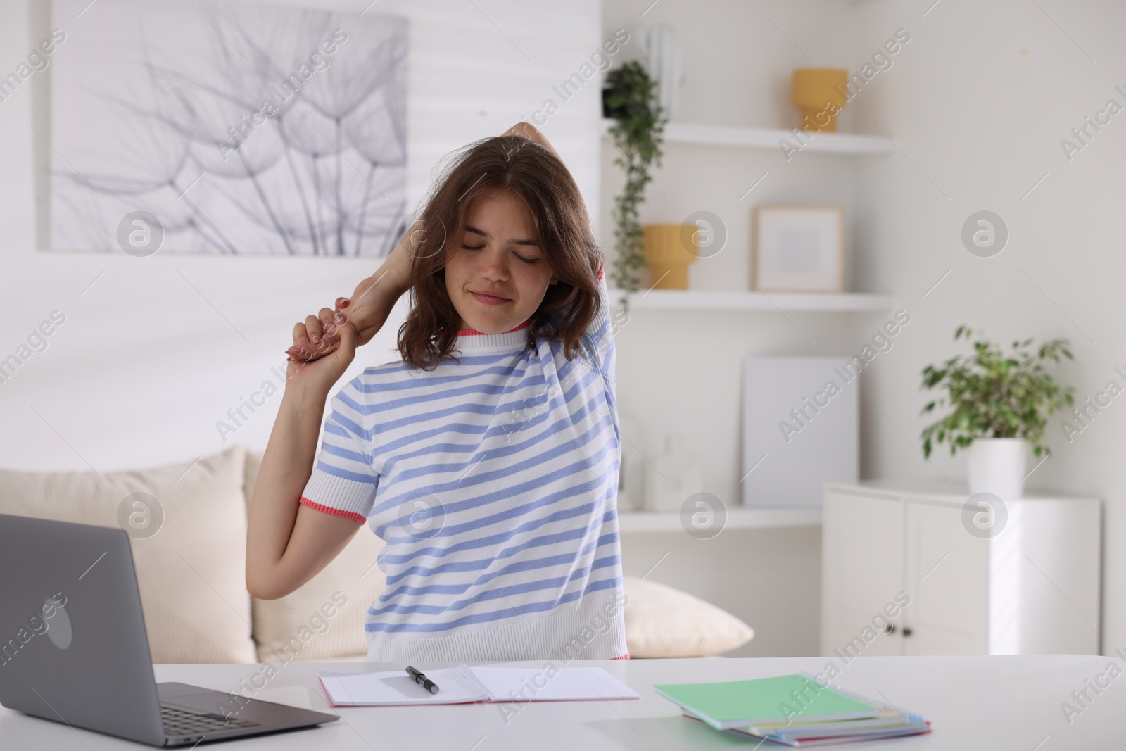 Photo of Beautiful teenage girl stretching at table indoors, space for text