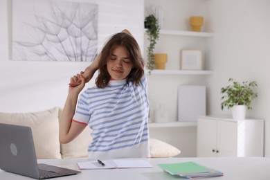 Photo of Beautiful teenage girl stretching at table indoors, space for text