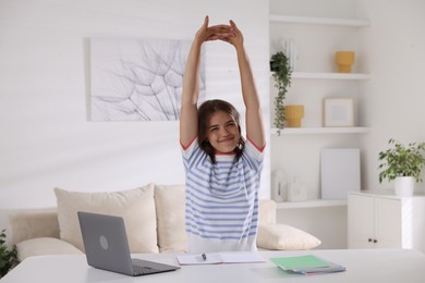 Photo of Beautiful teenage girl stretching at table indoors