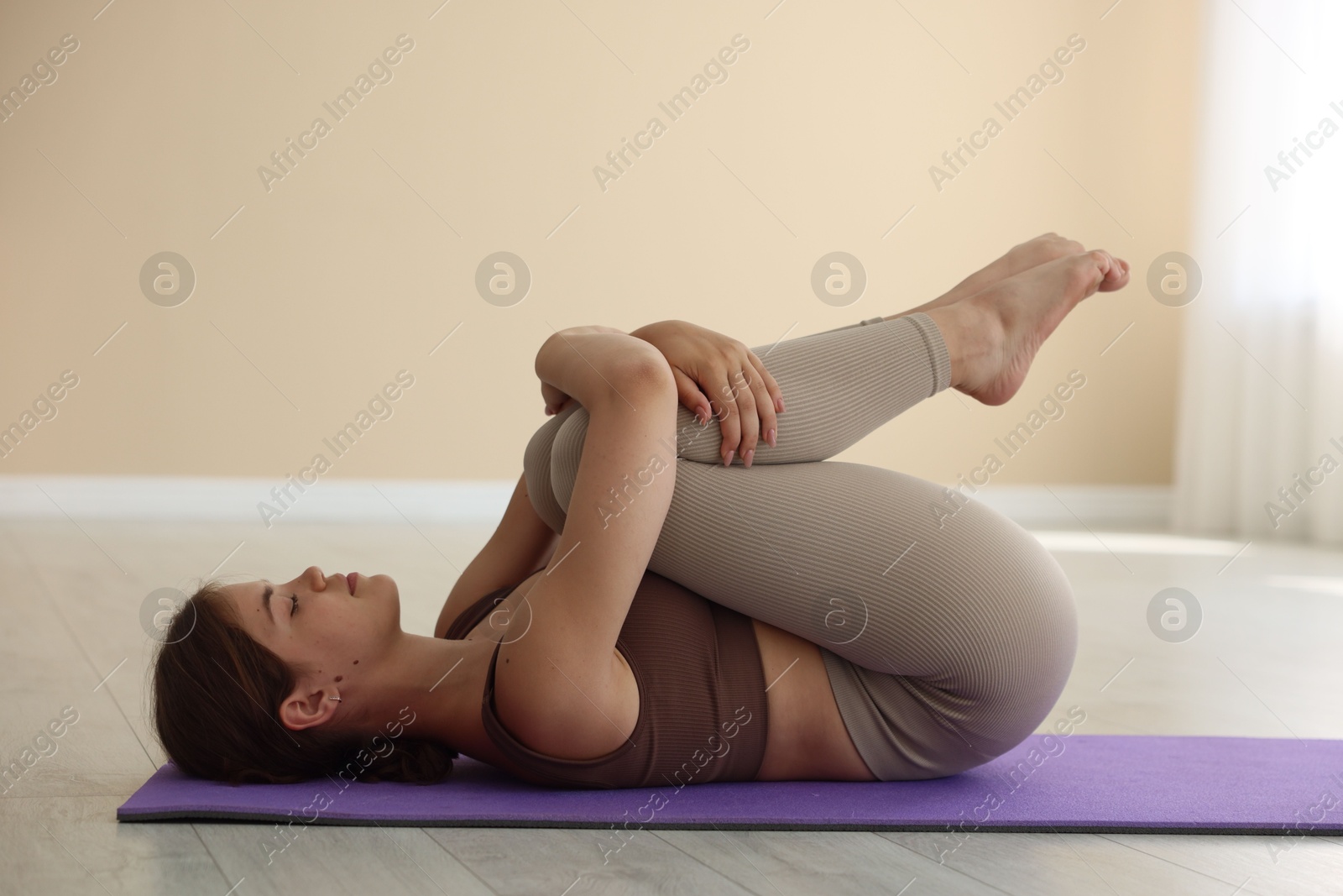 Photo of Teenage girl in sportswear stretching on mat indoors