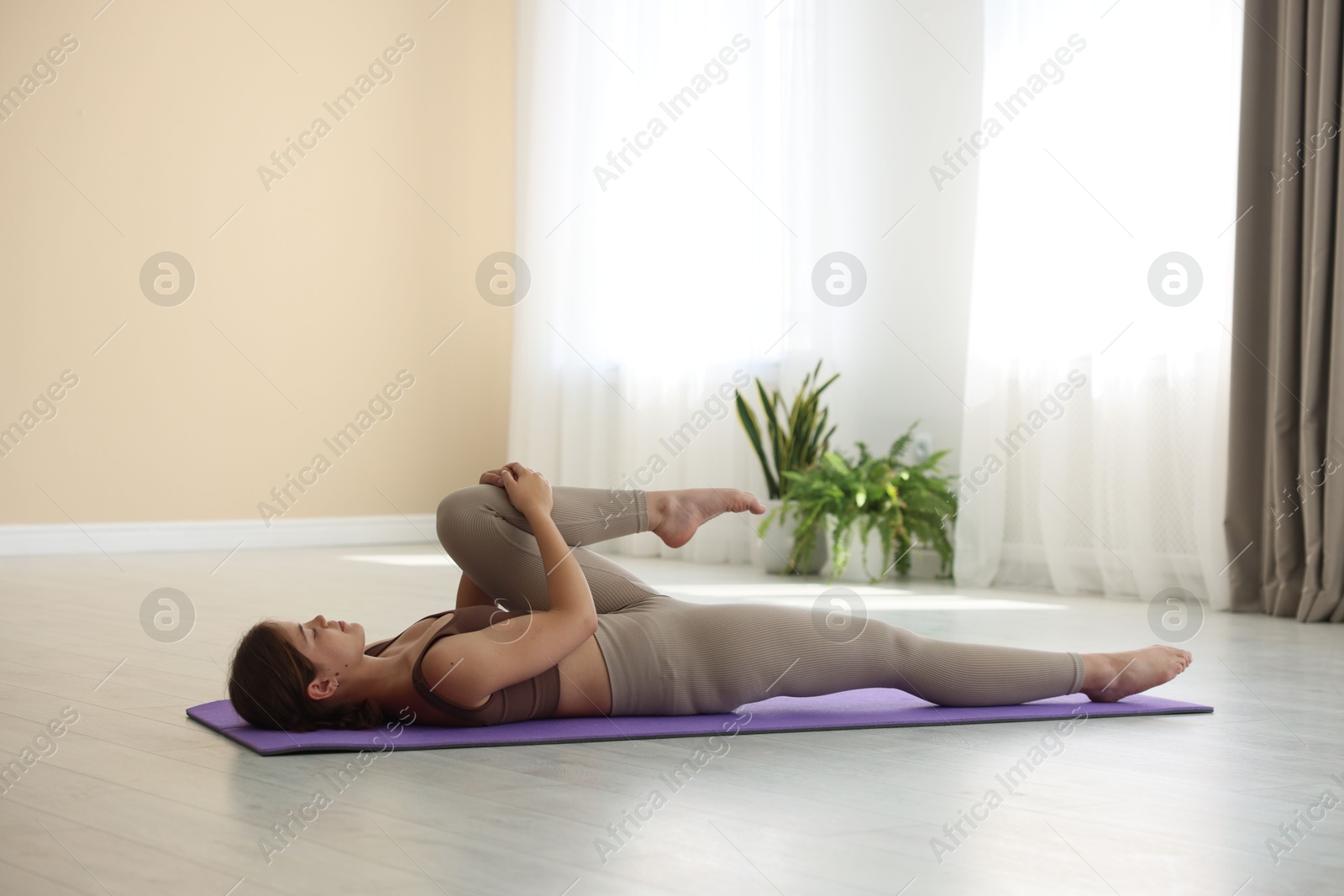 Photo of Teenage girl in sportswear stretching on mat indoors