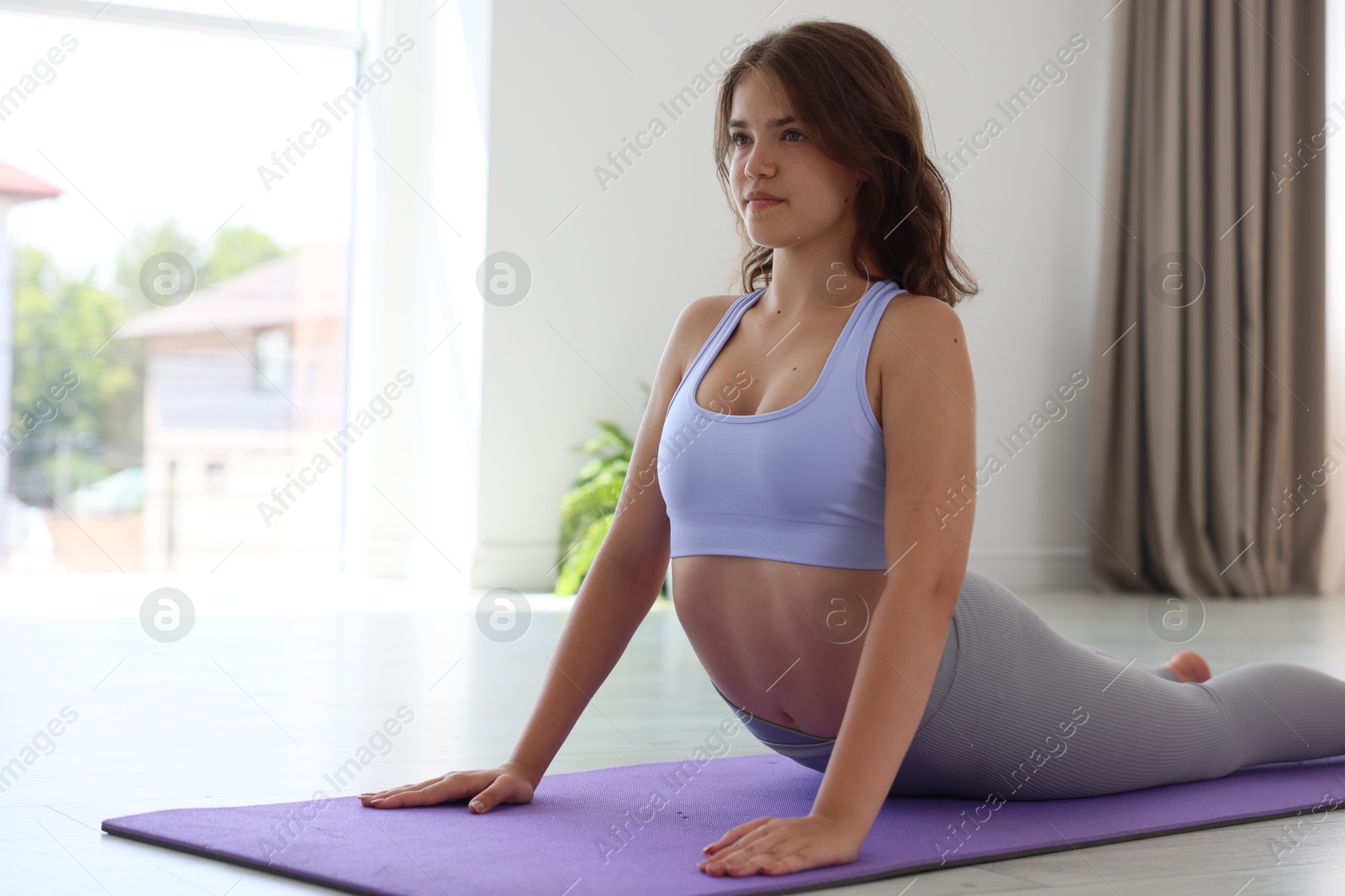 Teenage girl in sportswear stretching on mat indoors, space for text Photo of Teenage girl in sportswear stretching on mat indoors, space for text