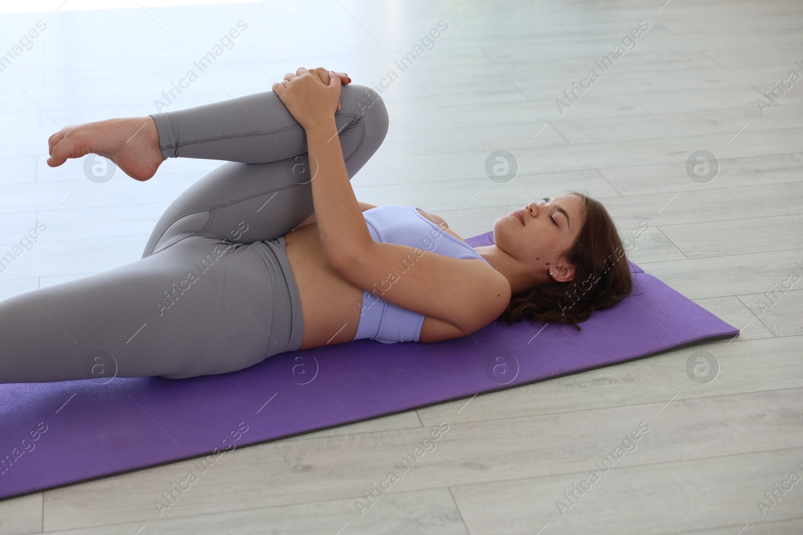 Teenage girl in sportswear stretching on mat indoors Photo of Teenage girl in sportswear stretching on mat indoors