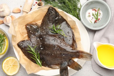 Photo of Fresh raw flounder fish and spices on light grey table, flat lay. Seafood