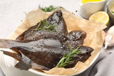 Photo of Fresh raw flounder fish and spices on light grey table, closeup. Seafood