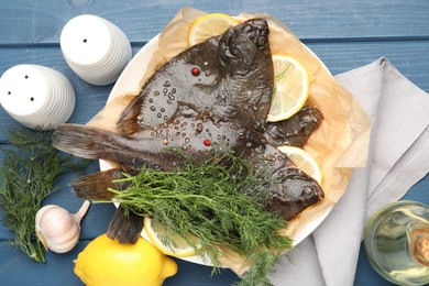 Photo of Fresh raw flounder fish and spices on blue wooden table, flat lay. Seafood