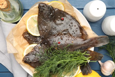 Photo of Fresh raw flounder fish and spices on blue wooden table, flat lay. Seafood