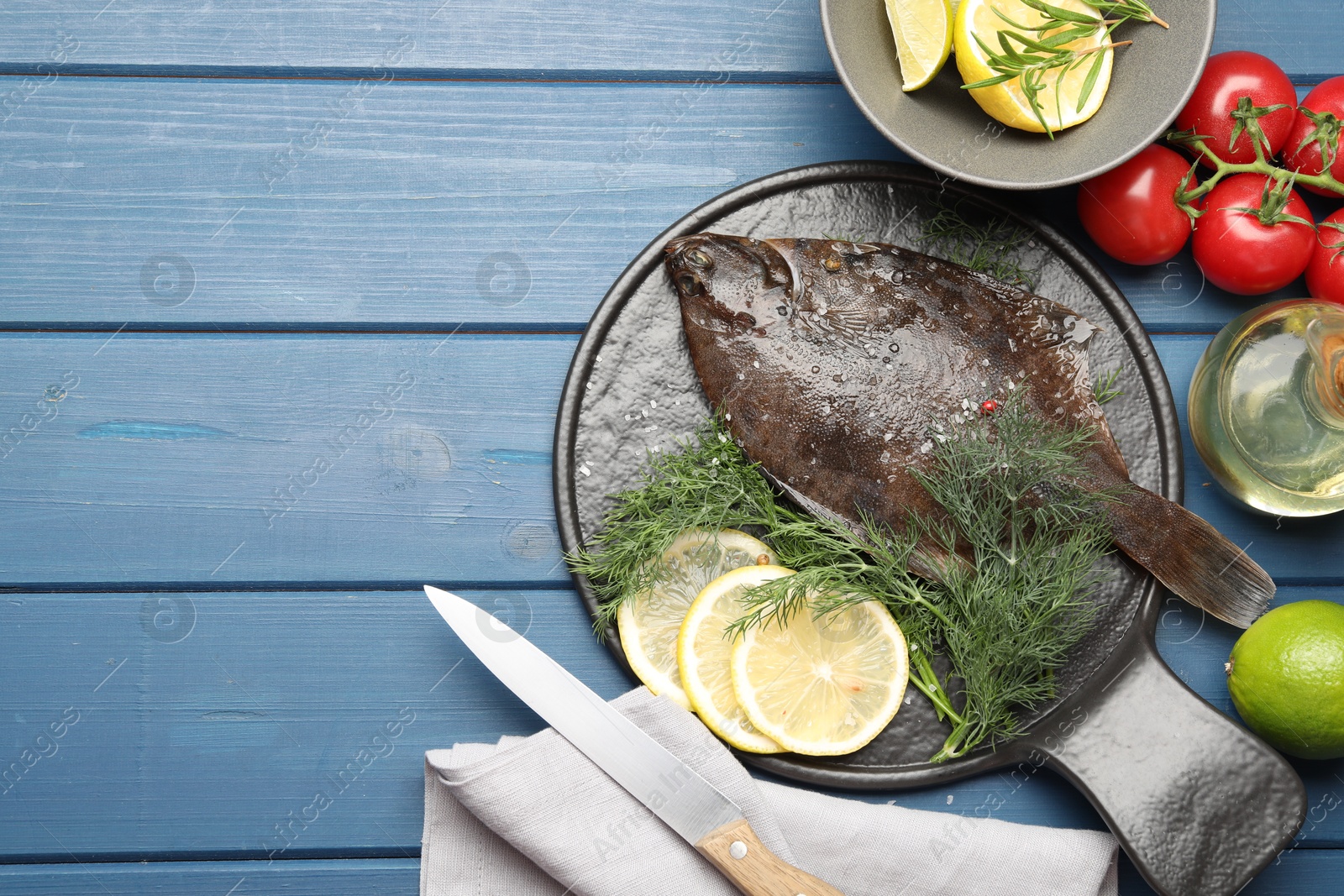 Seafood. Fresh raw flounder fish, ingredients and knife on blue wooden table, flat lay. Space for text Photo of Seafood. Fresh raw flounder fish, ingredients and knife on blue wooden table, flat lay. Space for text