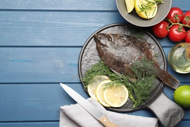 Photo of Seafood. Fresh raw flounder fish, ingredients and knife on blue wooden table, flat lay. Space for text