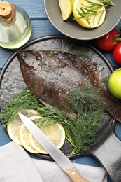 Photo of Fresh raw flounder fish, ingredients and knife on blue wooden table, flat lay. Seafood