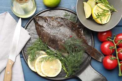 Photo of Fresh raw flounder fish, ingredients and knife on blue wooden table, flat lay. Seafood