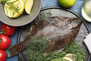 Photo of Fresh raw flounder fish and ingredients on blue wooden table, flat lay. Seafood