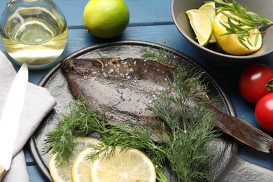 Photo of Fresh raw flounder fish, ingredients and knife on blue wooden table, above view. Seafood