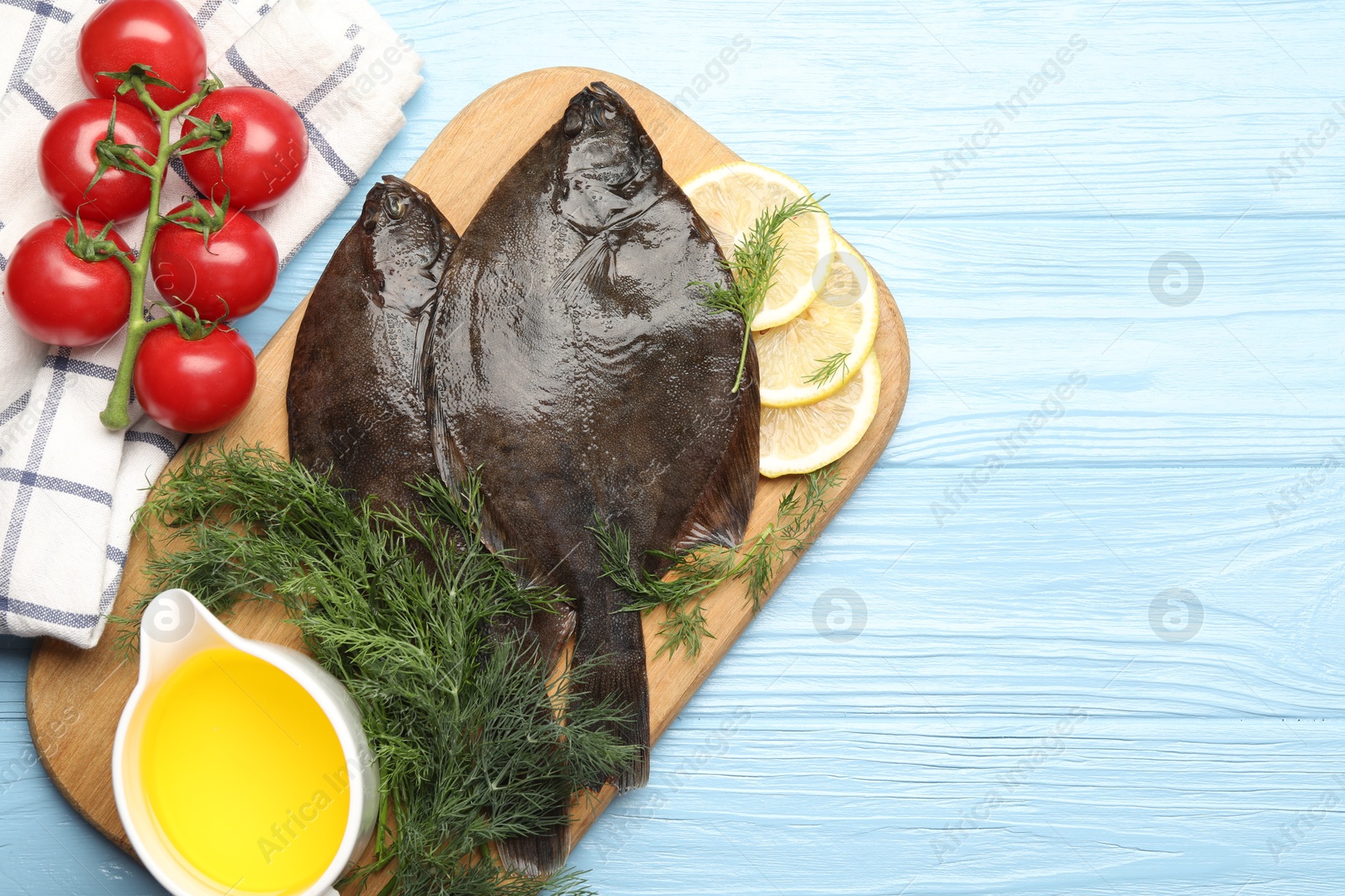 Photo of Seafood. Fresh raw flounder fish and ingredients on light blue wooden table, flat lay. Space for text