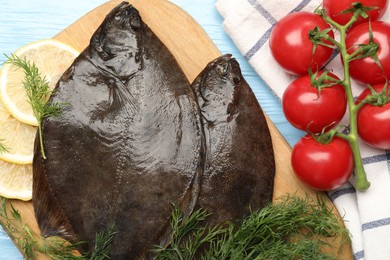 Photo of Fresh raw flounder fish and ingredients on light blue wooden table, flat lay. Seafood