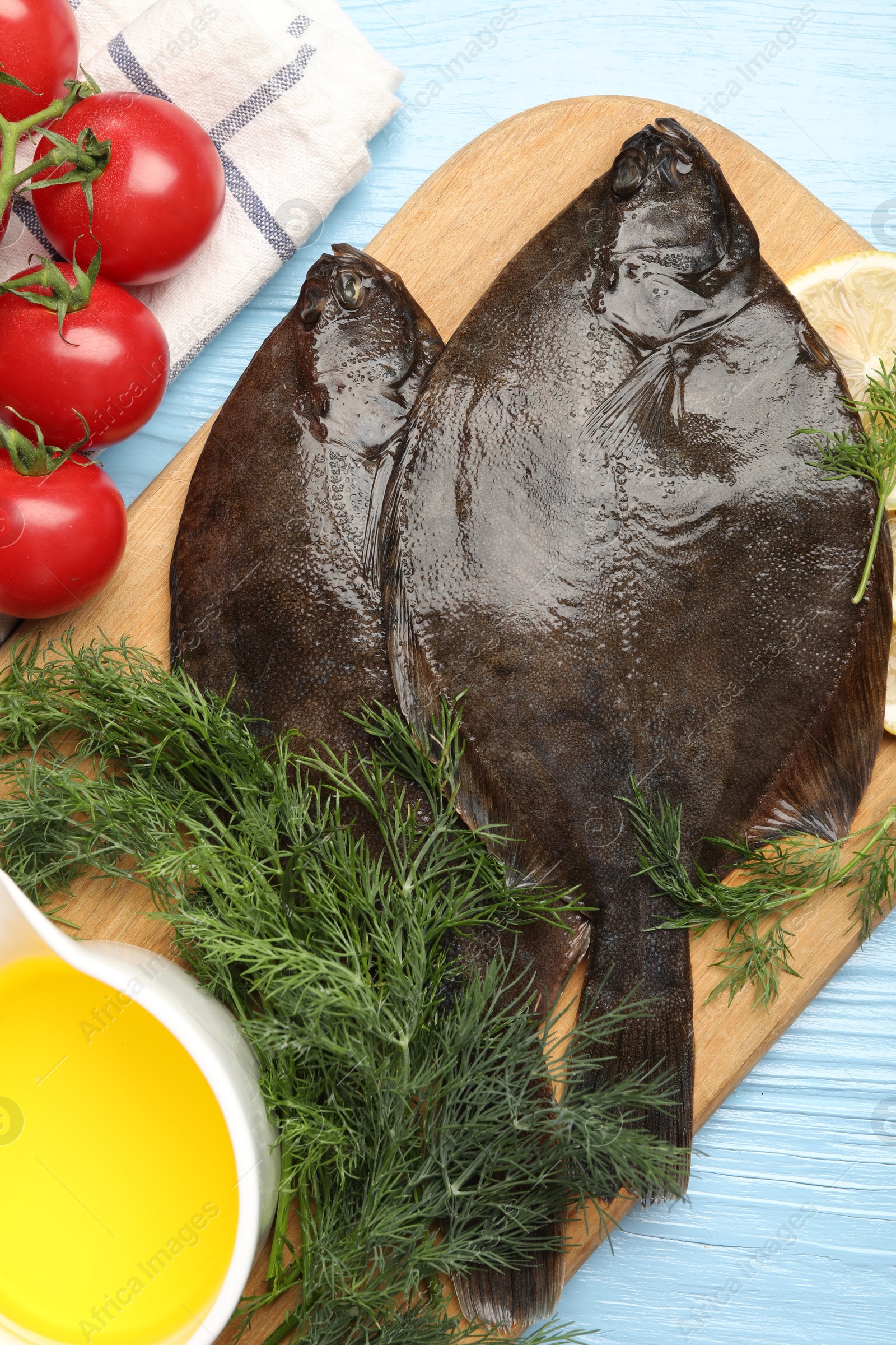 Fresh raw flounder fish and ingredients on light blue wooden table, flat lay. Seafood Photo of Fresh raw flounder fish and ingredients on light blue wooden table, flat lay. Seafood