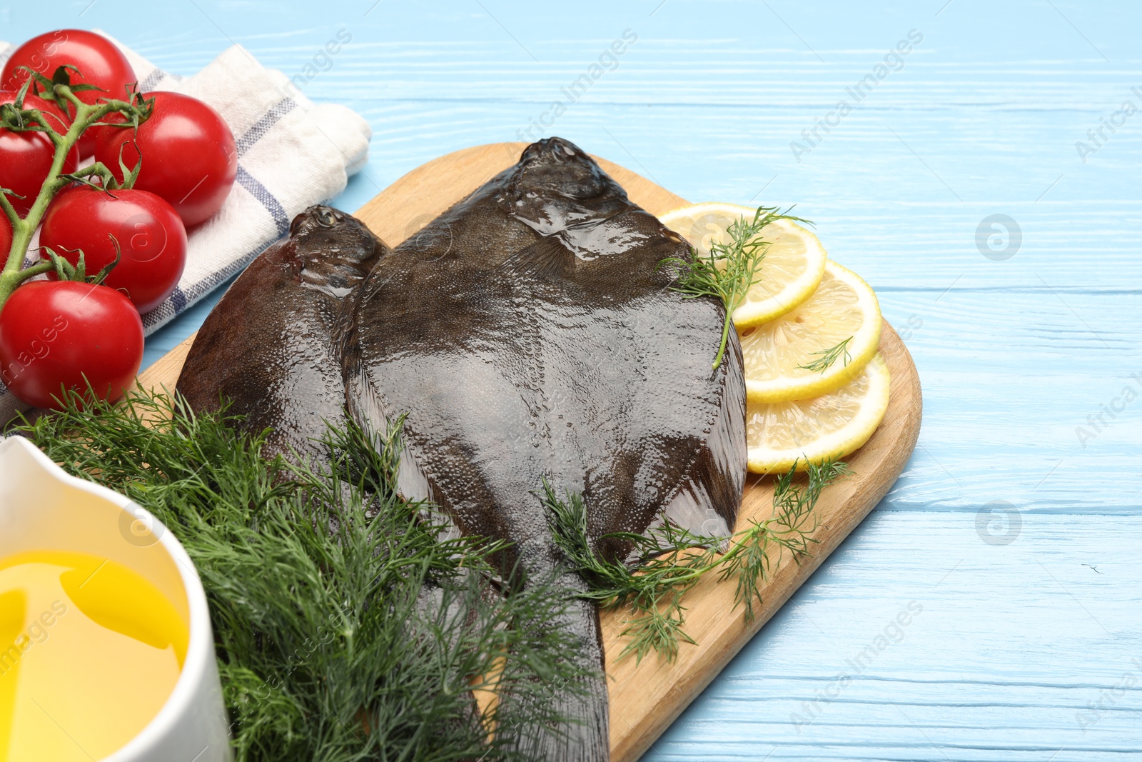 Seafood. Fresh raw flounder fish and ingredients on light blue wooden table, closeup. Space for text Photo of Seafood. Fresh raw flounder fish and ingredients on light blue wooden table, closeup. Space for text