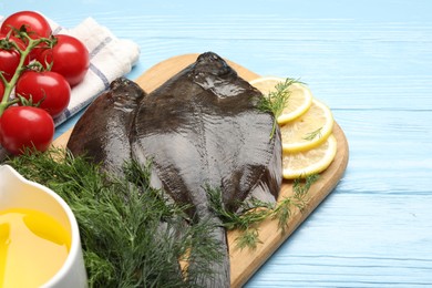 Photo of Seafood. Fresh raw flounder fish and ingredients on light blue wooden table, closeup. Space for text