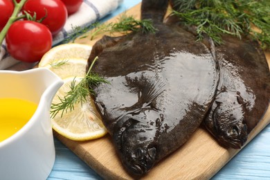Photo of Fresh raw flounder fish and ingredients on light blue wooden table, closeup. Seafood