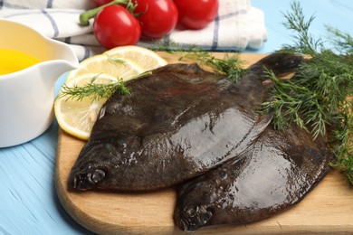 Photo of Fresh raw flounder fish and ingredients on light blue wooden table, closeup. Seafood