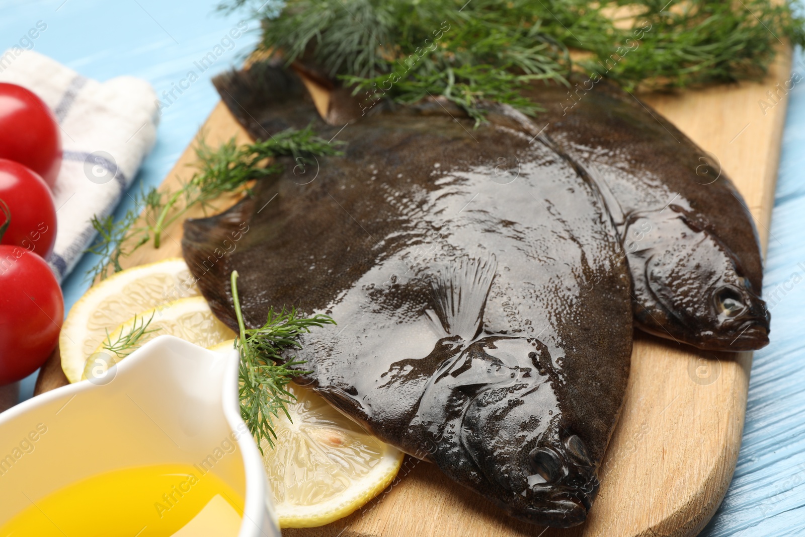 Photo of Fresh raw flounder fish and ingredients on light blue wooden table, closeup. Seafood
