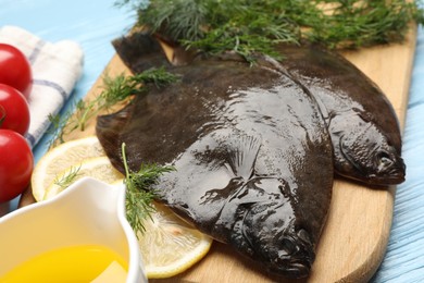Photo of Fresh raw flounder fish and ingredients on light blue wooden table, closeup. Seafood