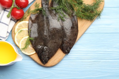 Photo of Seafood. Fresh raw flounder fish and ingredients on light blue wooden table, flat lay. Space for text