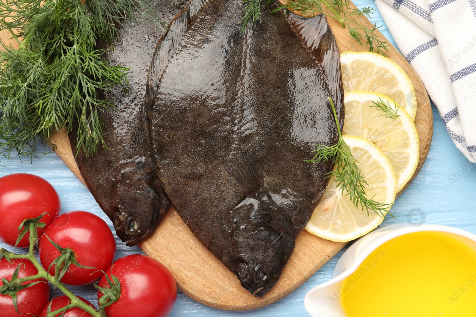 Fresh raw flounder fish and ingredients on light blue wooden table, flat lay. Seafood Photo of Fresh raw flounder fish and ingredients on light blue wooden table, flat lay. Seafood