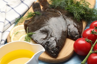 Photo of Fresh raw flounder fish and ingredients on light blue wooden table, closeup. Seafood