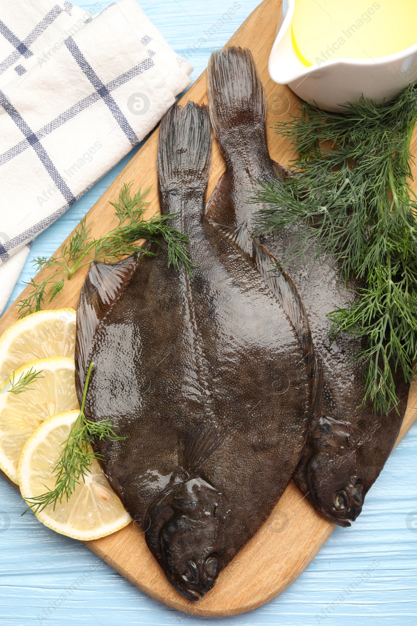 Photo of Fresh raw flounder fish and spices on light blue wooden table, top view. Seafood