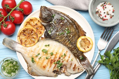 Photo of Tasty roasted flounder fish with herbs and lemon slices served on light blue wooden table, flat lay. Homemade seafood dish