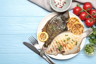 Photo of Homemade seafood dish. Tasty roasted flounder fish with herbs and lemon slices served on light blue wooden table, flat lay. Space for text