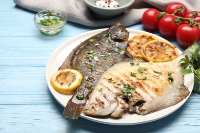 Photo of Tasty roasted flounder fish with herbs, lemon slices and tomatoes on light blue wooden table, closeup. Homemade seafood dish