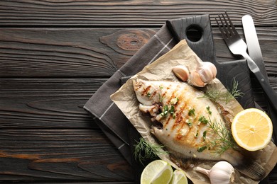 Photo of Homemade seafood dish. Tasty roasted flounder fish with spices served on wooden table, flat lay. Space for text