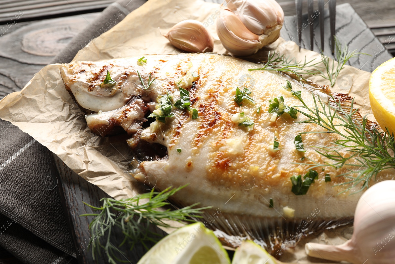 Photo of Tasty roasted flounder fish with spices served on wooden table, closeup. Homemade seafood dish