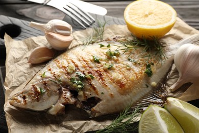 Photo of Tasty roasted flounder fish with spices served on wooden table, closeup. Homemade seafood dish