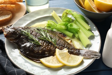 Photo of Tasty roasted flounder fish with celery served on blue wooden table, closeup. Homemade seafood dish
