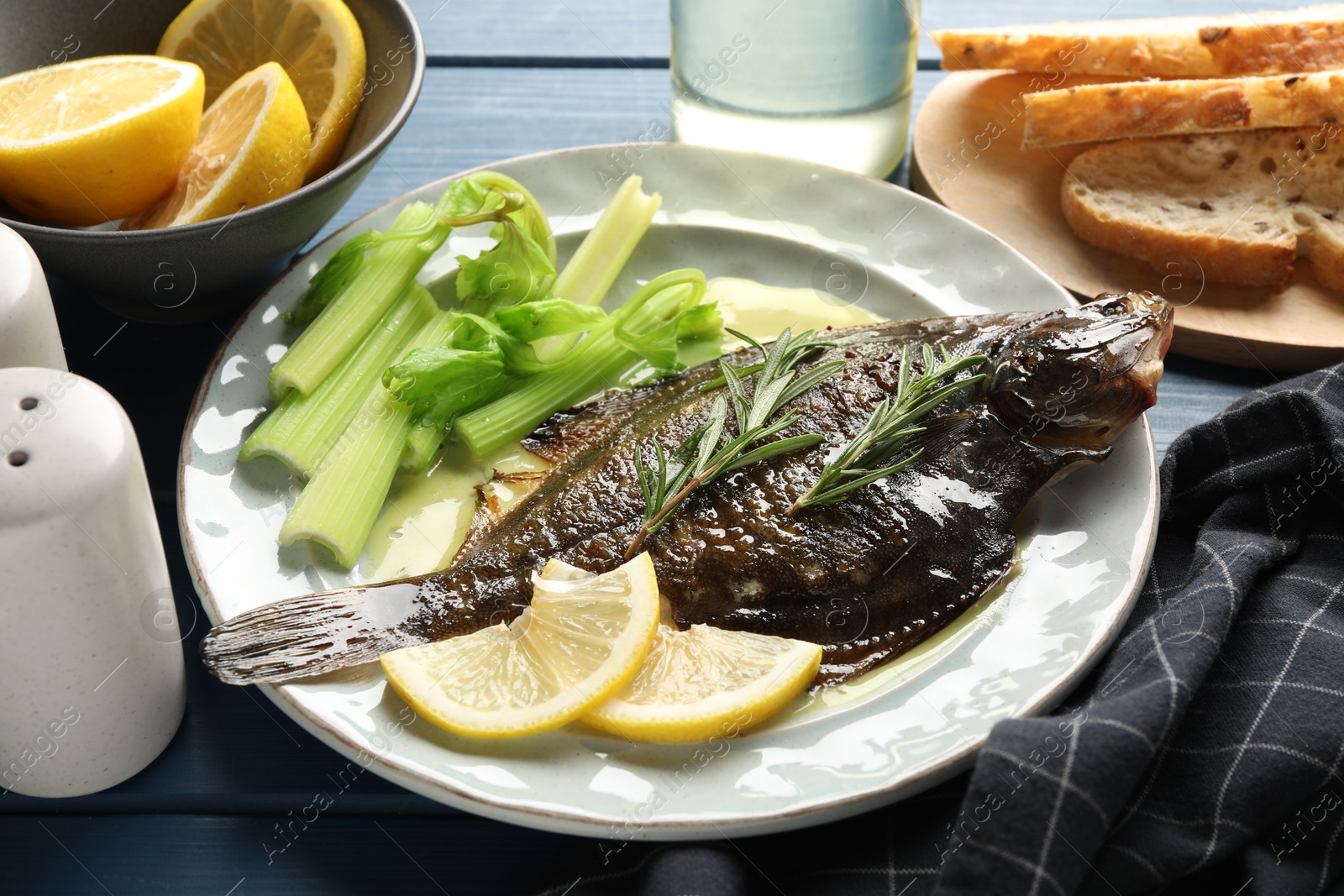 Photo of Tasty roasted flounder fish with celery served on blue wooden table, closeup. Homemade seafood dish