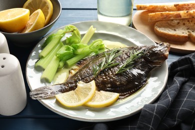 Photo of Tasty roasted flounder fish with celery served on blue wooden table, closeup. Homemade seafood dish