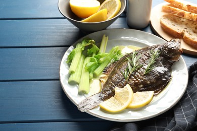 Photo of Tasty roasted flounder fish with celery served on blue wooden table, closeup. Homemade seafood dish
