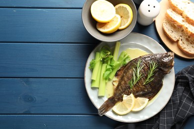 Photo of Homemade seafood dish. Tasty roasted flounder fish with celery served on blue wooden table, flat lay. Space for text