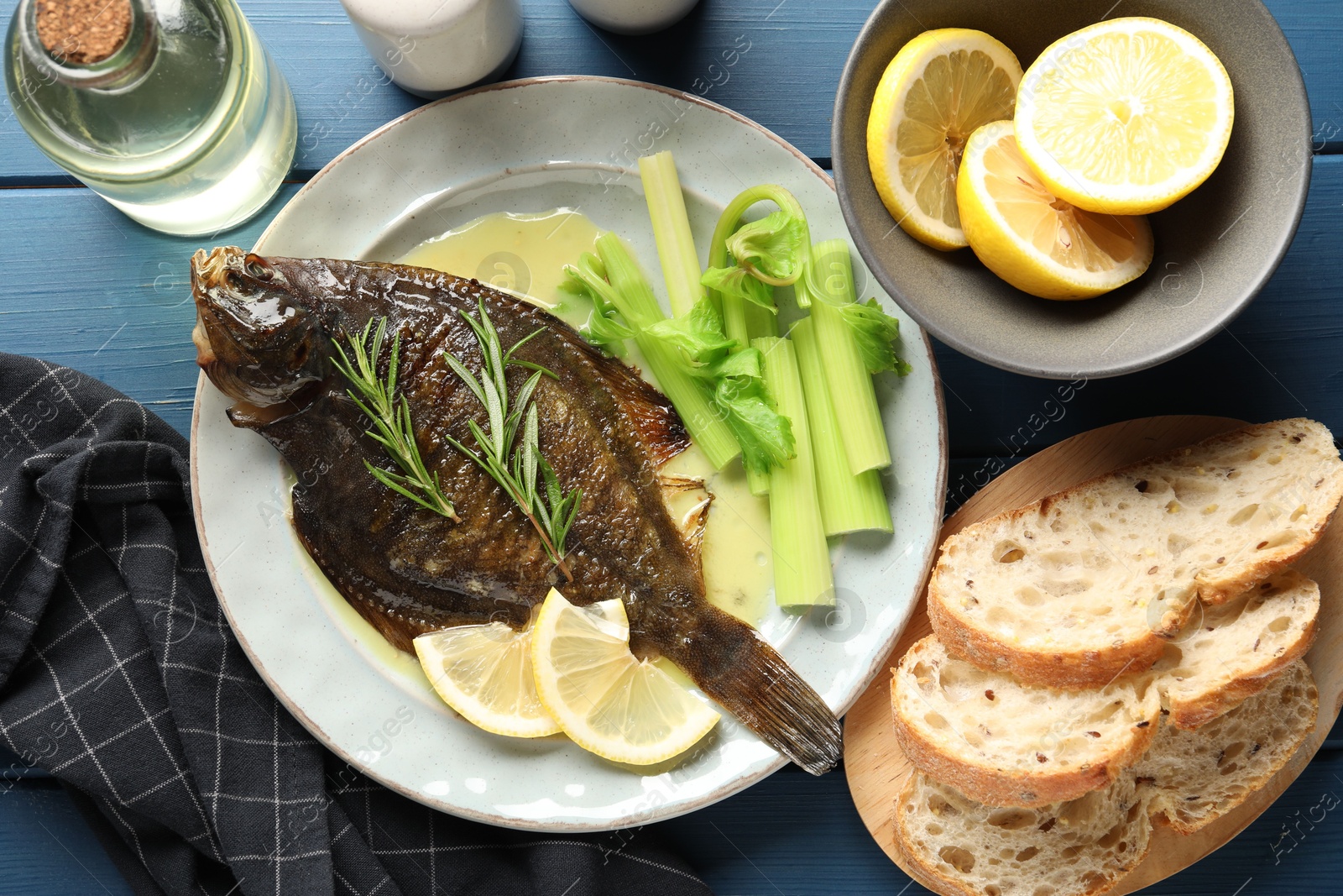 Photo of Tasty roasted flounder fish with celery served on blue wooden table, flat lay. Homemade seafood dish