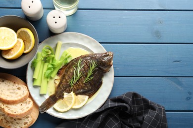Photo of Homemade seafood dish. Tasty roasted flounder fish with celery served on blue wooden table, flat lay. Space for text