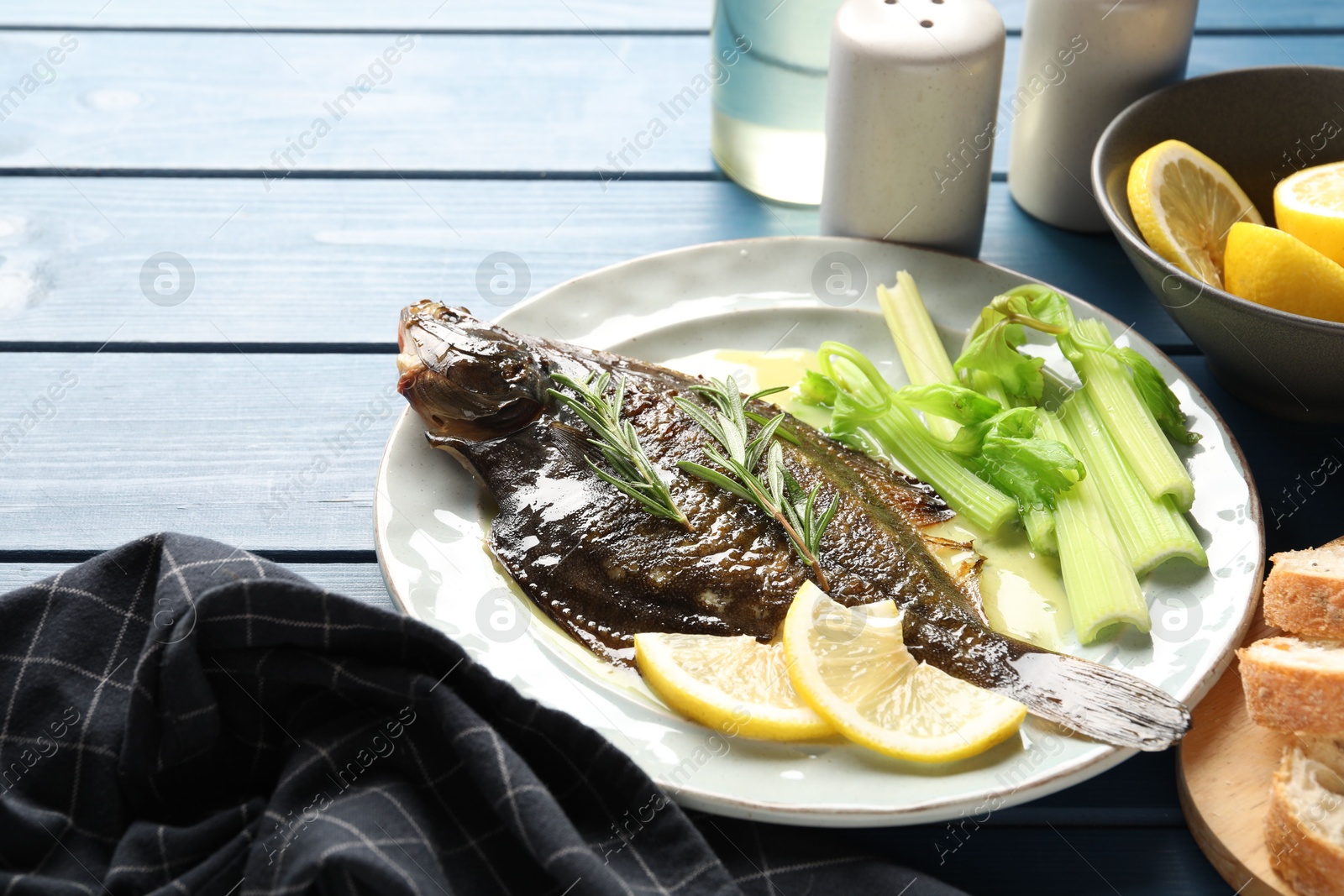 Photo of Tasty roasted flounder fish with celery served on blue wooden table, closeup. Homemade seafood dish