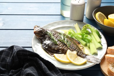 Photo of Tasty roasted flounder fish with celery served on blue wooden table, closeup. Homemade seafood dish
