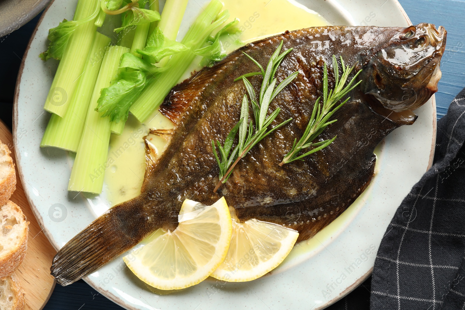 Photo of Tasty roasted flounder fish with celery served on blue table, closeup. Homemade seafood dish